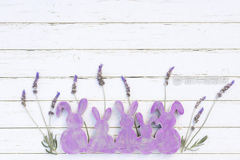 平坦的紫色木制复古复活节兔子形状与薰衣草和白色德文字母Frohe Ostern在白色木制背景与复制空间
